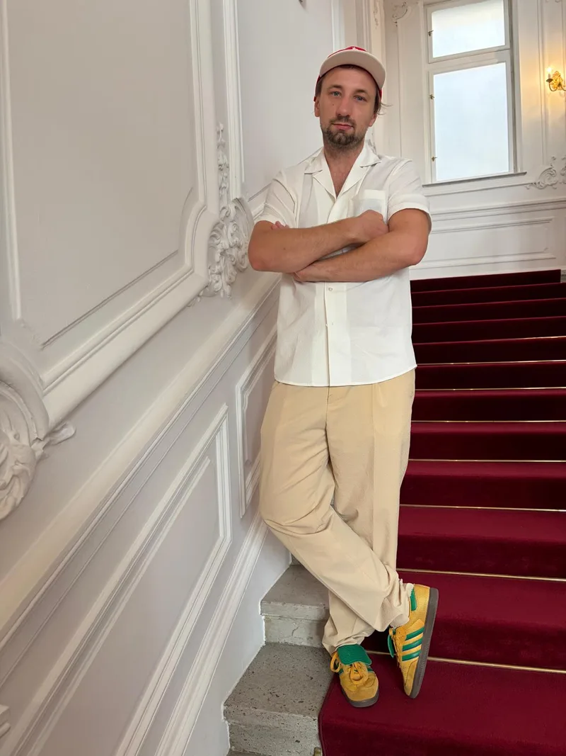 Christoph Klauke in weißem Hemd, angelehnt an eine Wand
