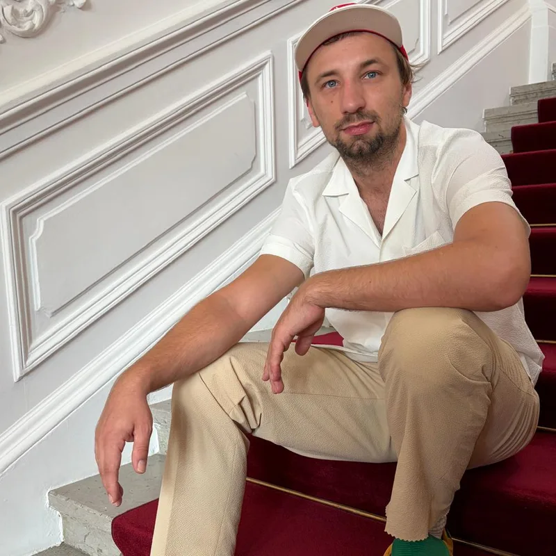 Christoph Klauke sitzt entspannt auf einer Treppe und lächelt leicht in die Kamera